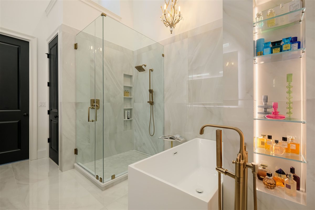 Primary bath with a freestanding tub and lit display shelving, Uptown primary suite