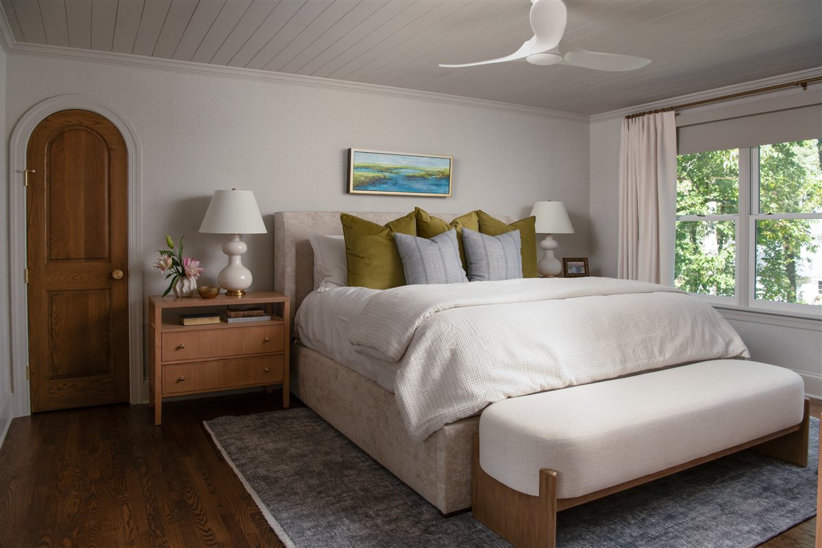Primary bedroom with a wood arched door and upholstered bed, Valencia Terrace addition