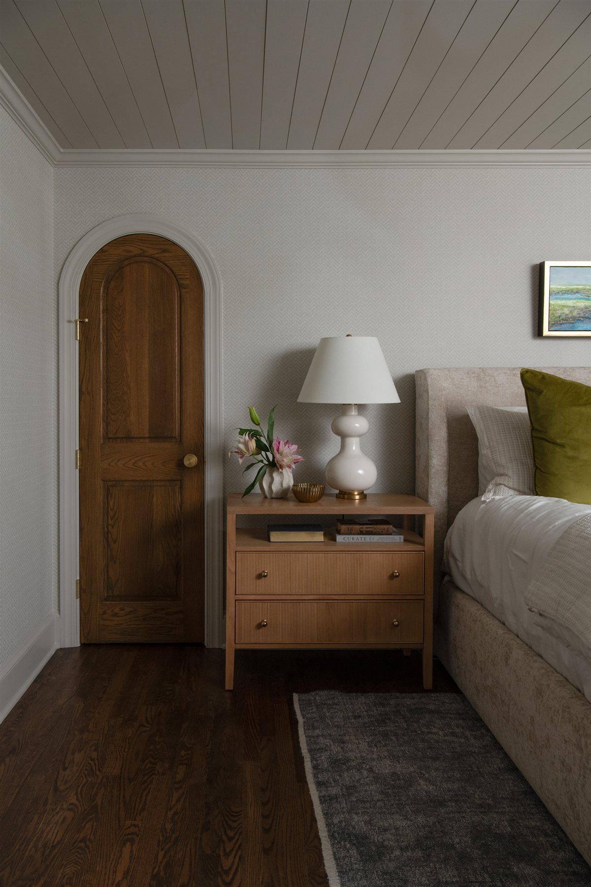 Bedside table with a lamp beside an arched wood door, Valencia Terrace addition