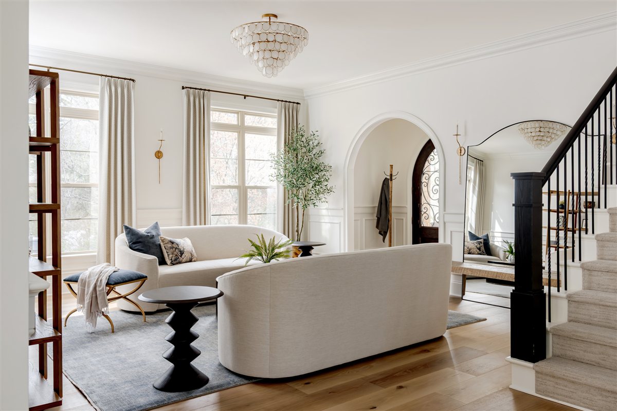 Living room with a curved sofa, arched doorway and staircase, Waxhaw whole-home renovation