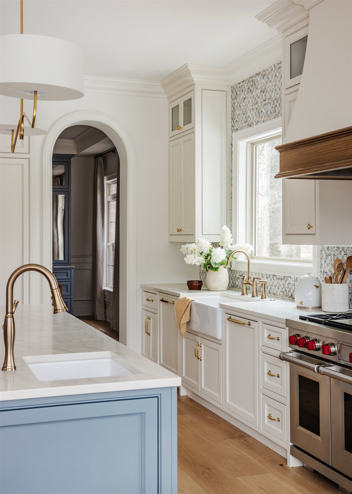 Blue cabinetry and a brass faucet beneath an arched doorway, Waxhaw renovation