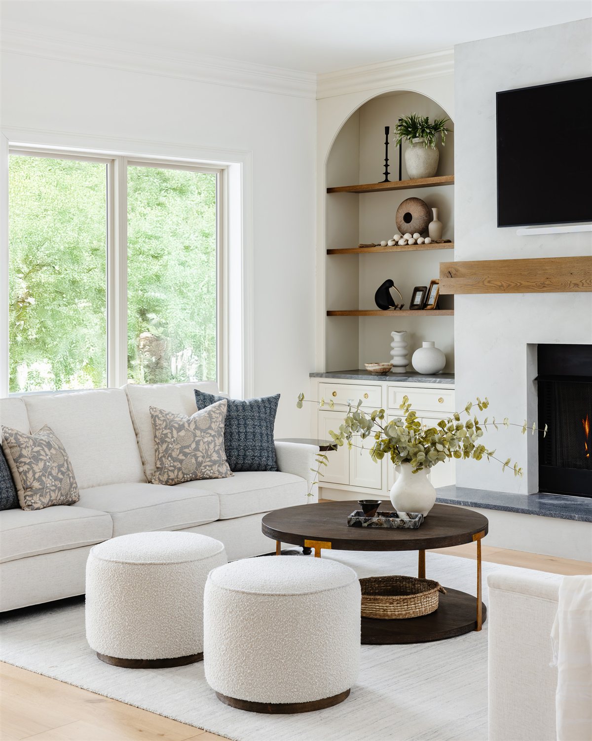 Family room with a white sectional, round ottomans and arched built-ins, Waxhaw renovation