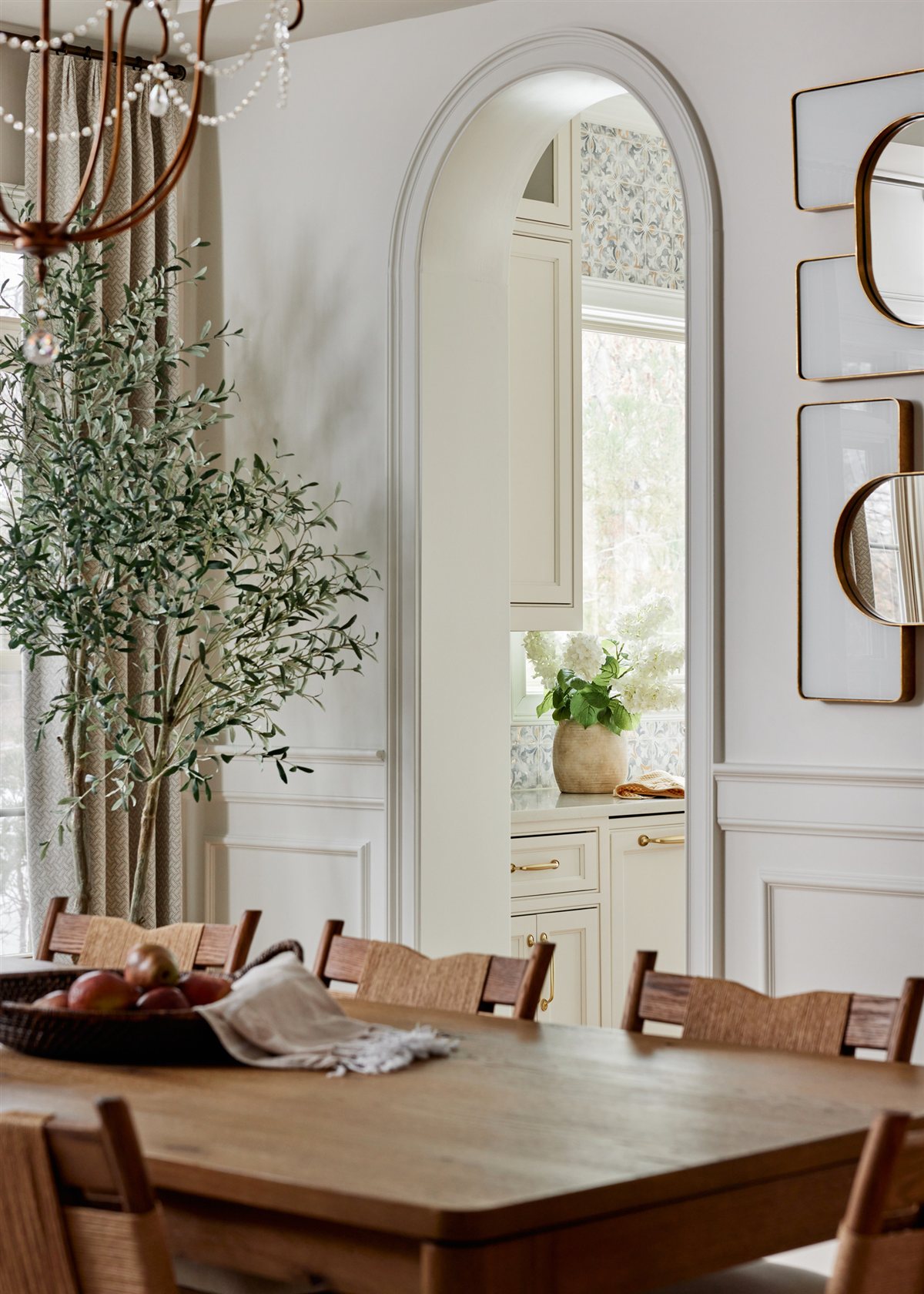 Dining area with arched mirrors and an olive tree, Waxhaw renovation