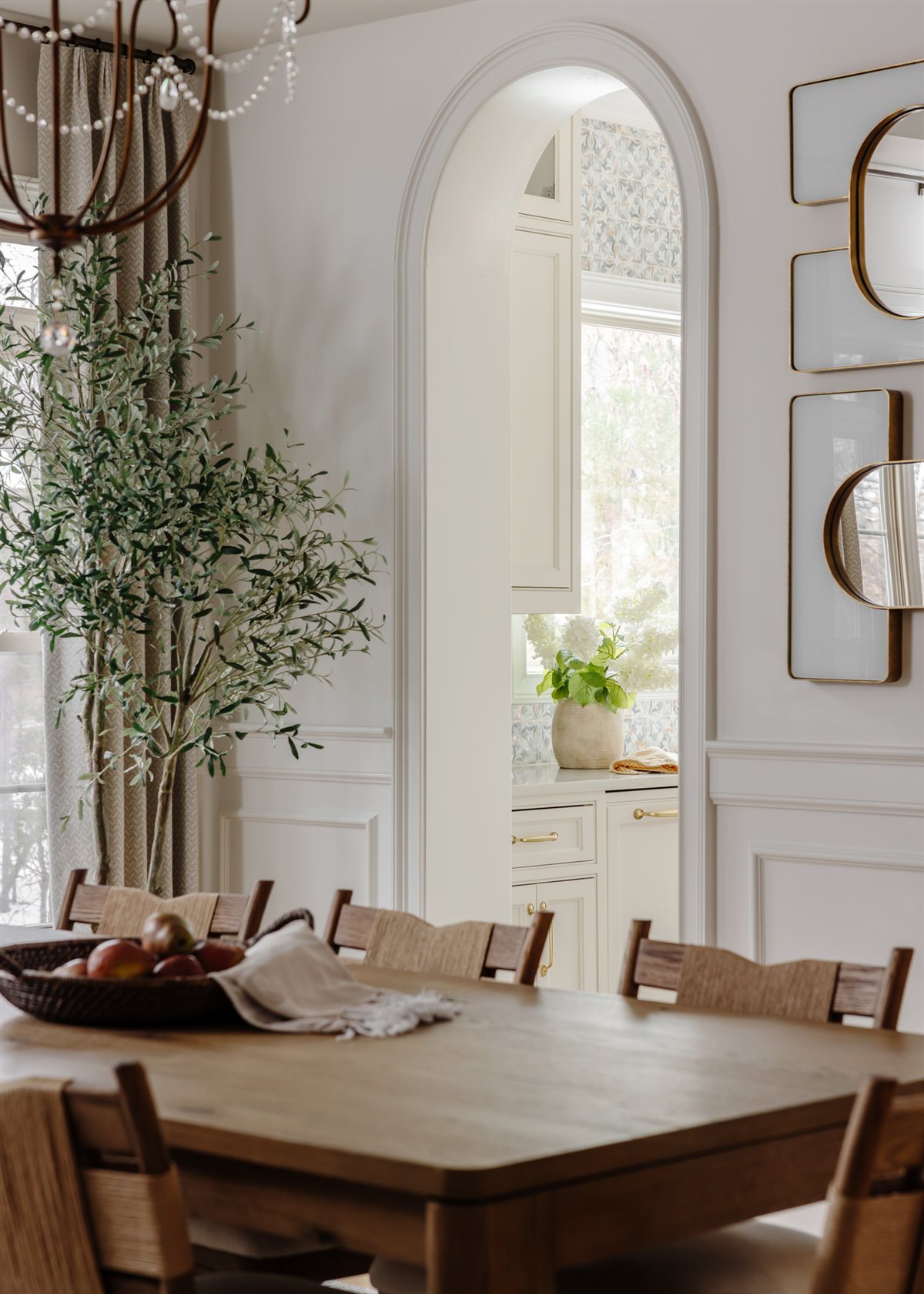 Dining area with arched mirrors on white paneled walls, Waxhaw renovation
