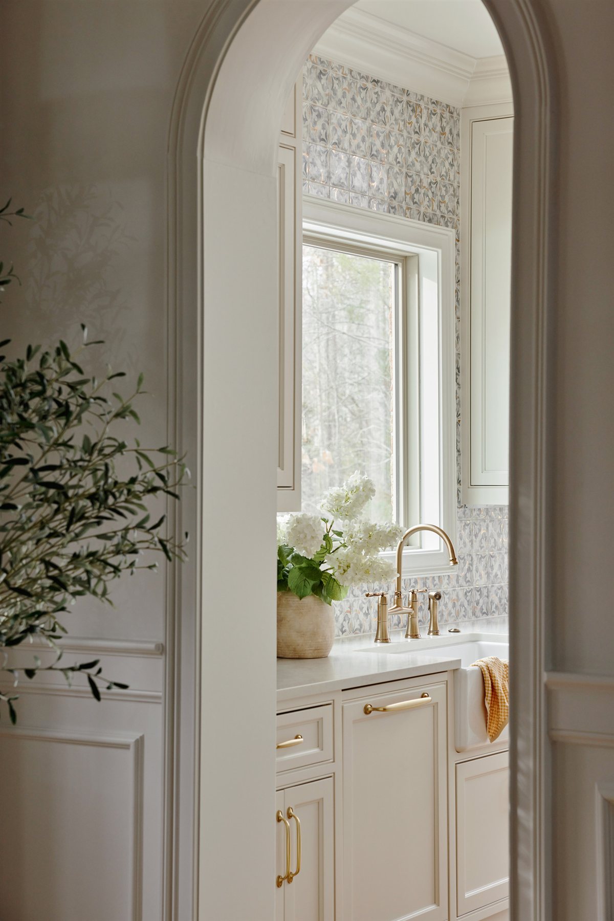 Arched opening into a powder room with floral wallpaper, Waxhaw renovation