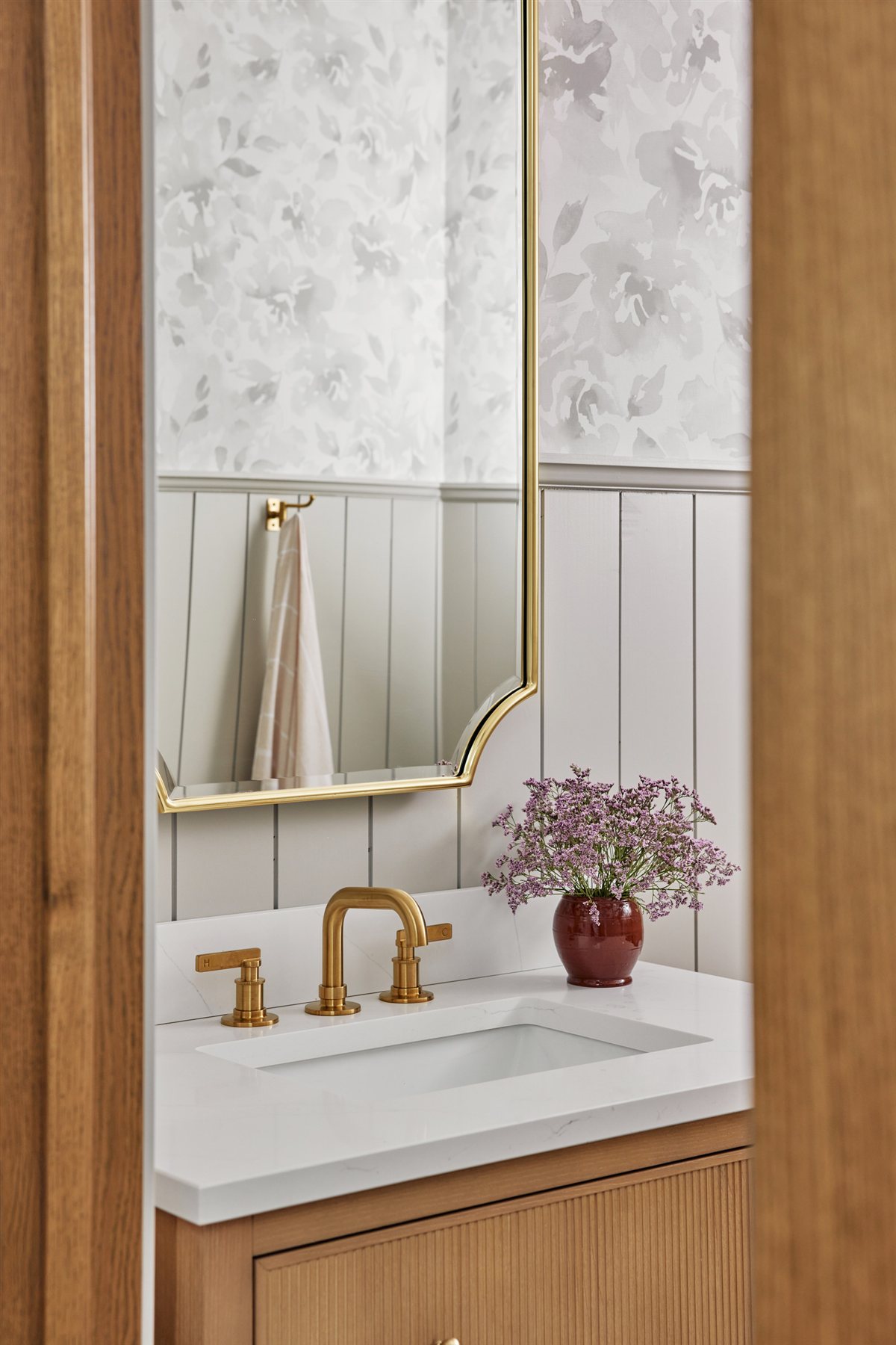 Powder room vanity with a brass faucet and arched mirror, Waxhaw renovation