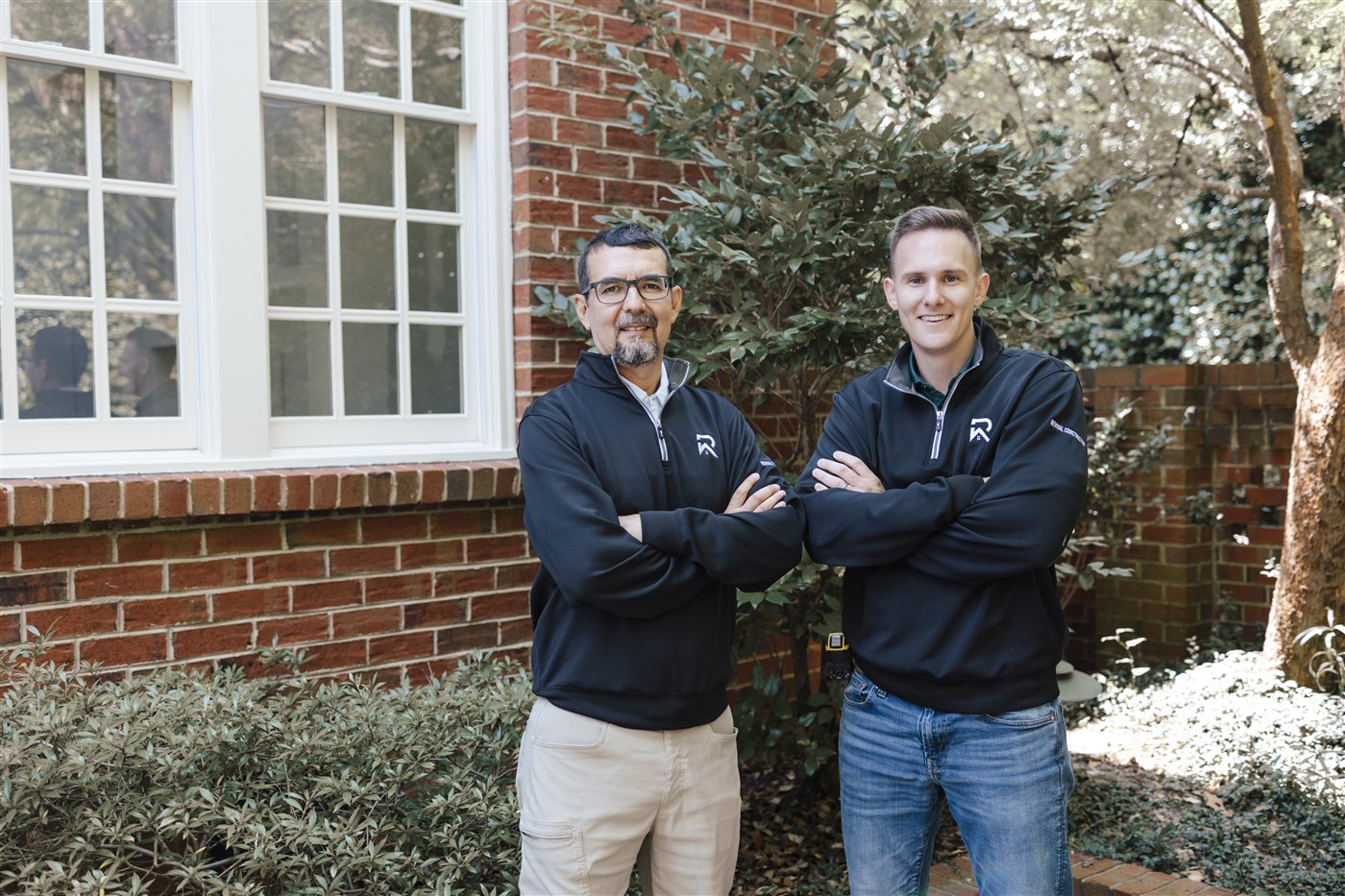 Owners Max Messenger and Esiquio Uribe Cortes, arms crossed outside a brick Charlotte home